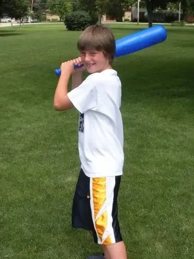 Alec mid-swing with a baseball bat on the lawn