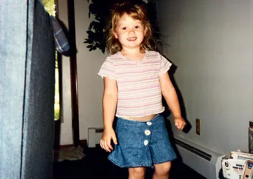 A little girl in a denim skirt, caught mid-step