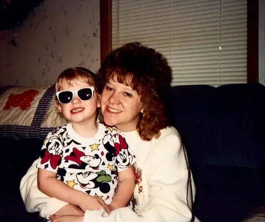 A child in sunglasses held close, both smiling